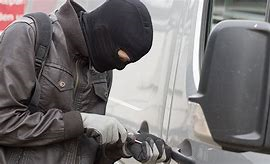 Close up of a man in a balaclava breaking a lock of a van in order to gain entry